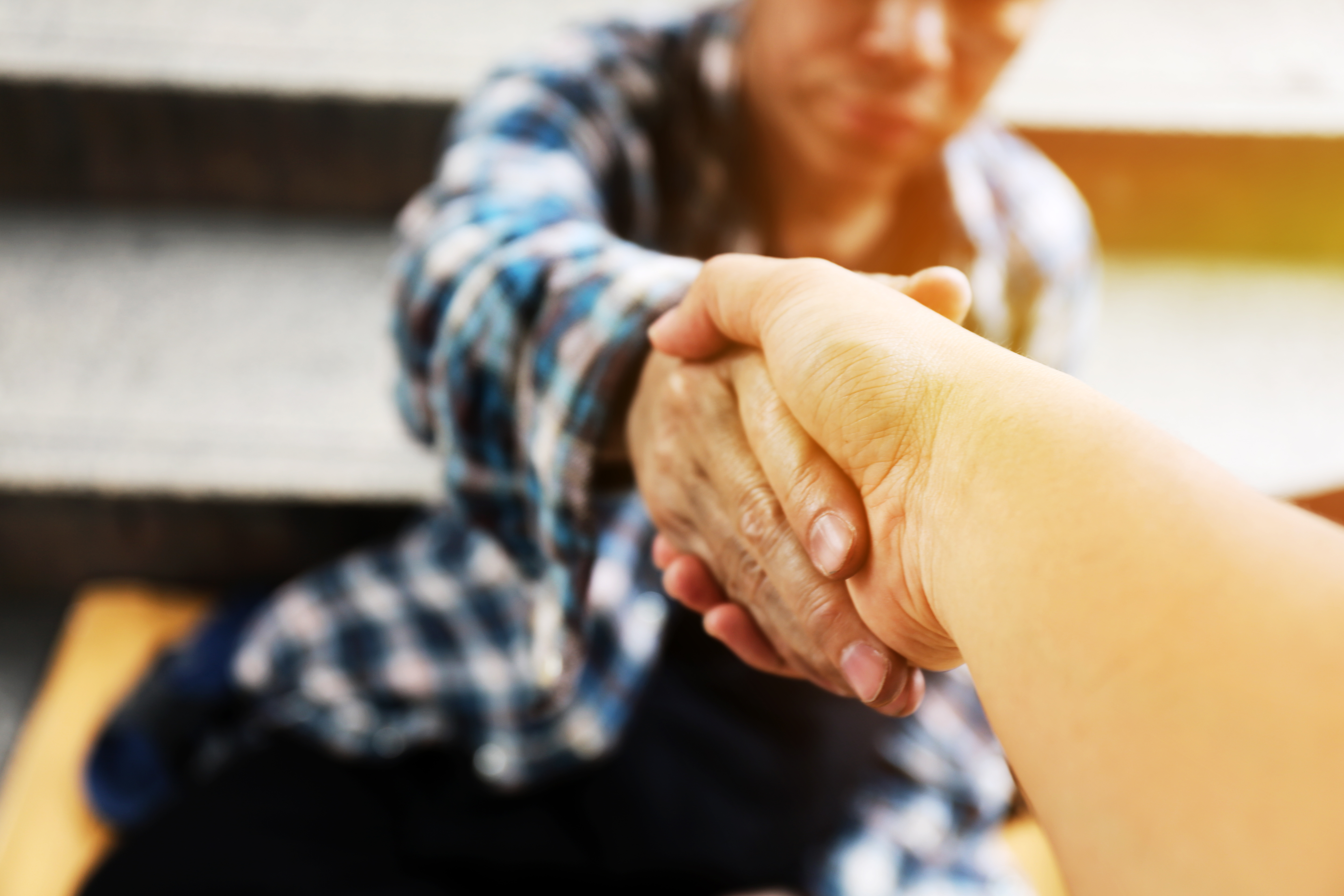 A person reaches out to help another person up from a sitting position.