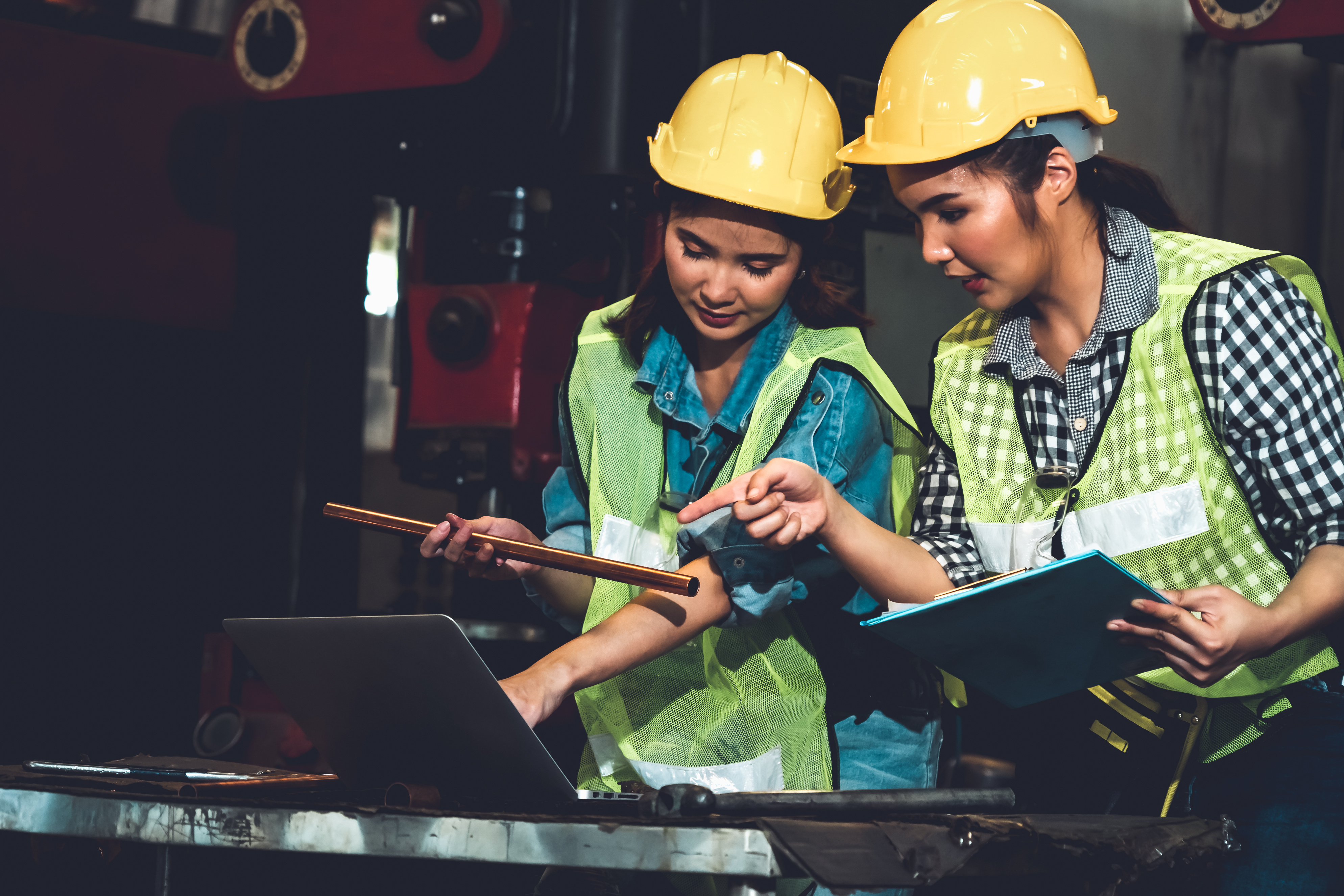 two woman with hard hats looking at a computer