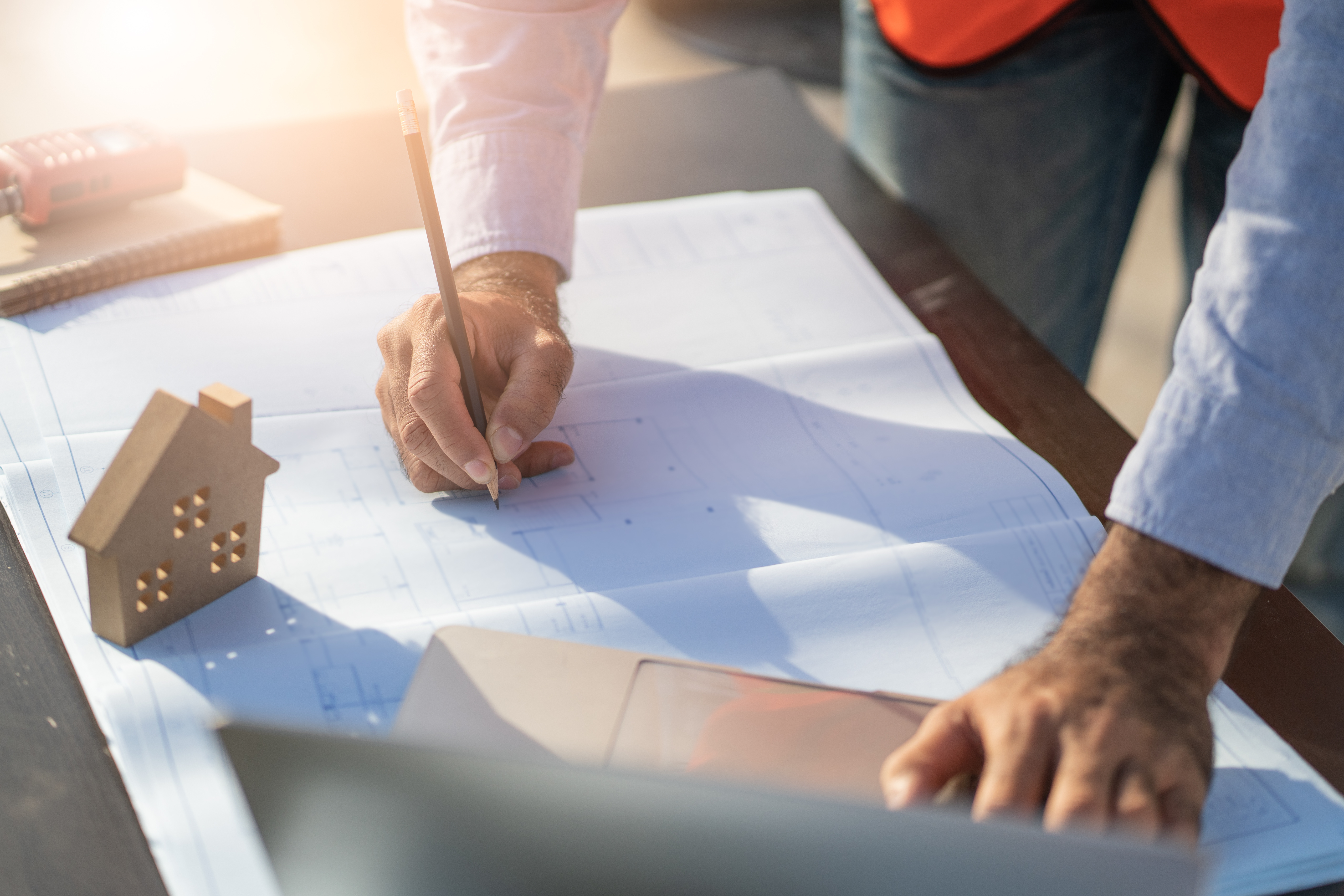 man planning with pencil in hand and a small wooden house