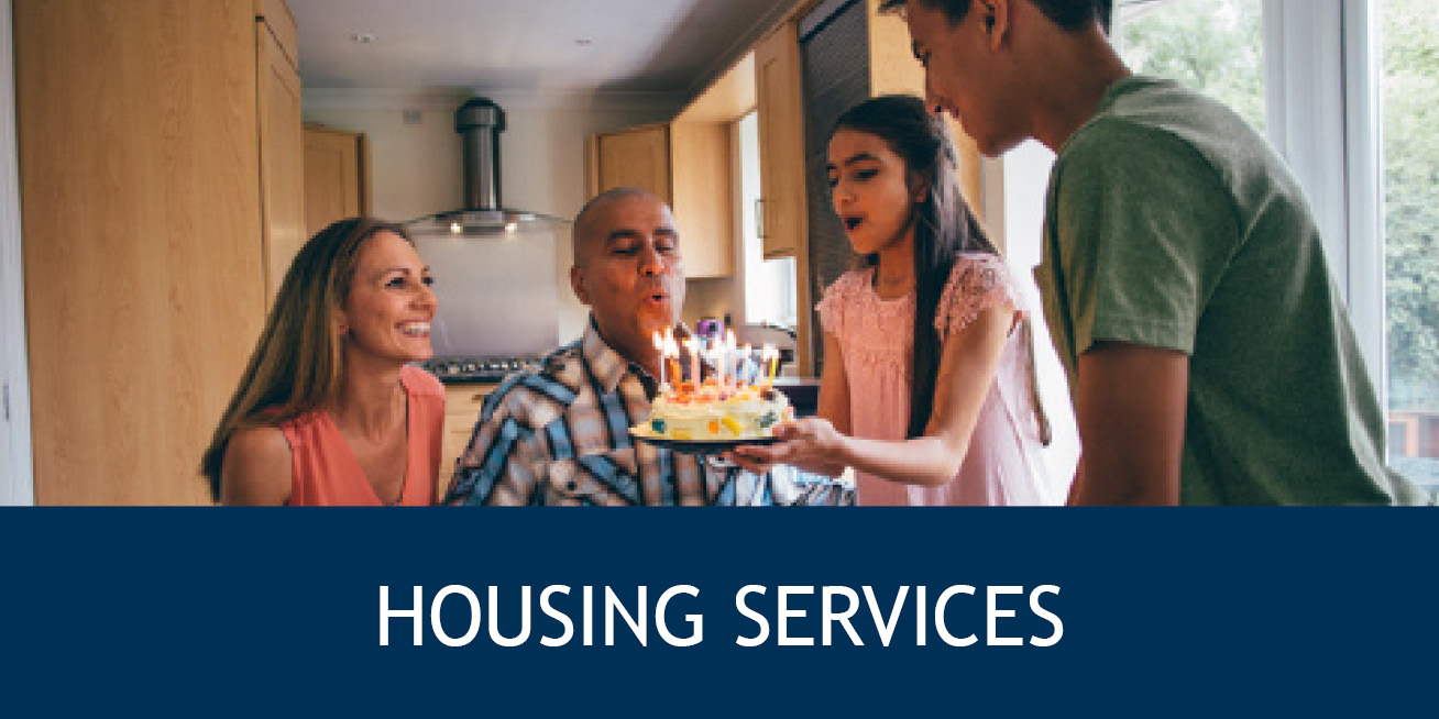 a man blowing out birthday candles surrounded by family with the words "housing services" underneath