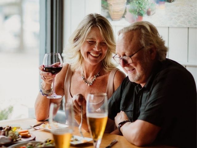 Smiling couple enjoying wine and food at a local restaurant.