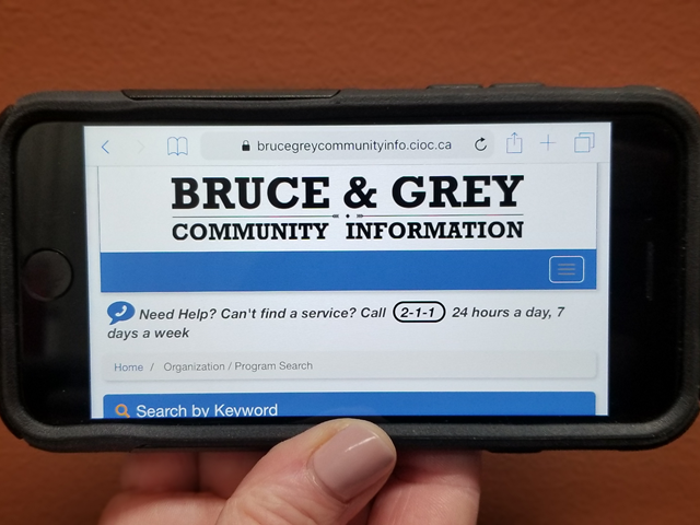 photo of cell phone with the bruce & grey community information website on it