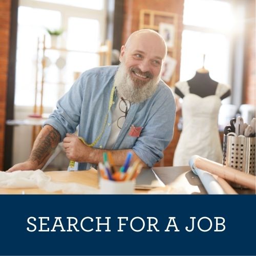 Man leaning on desk in dress shop.