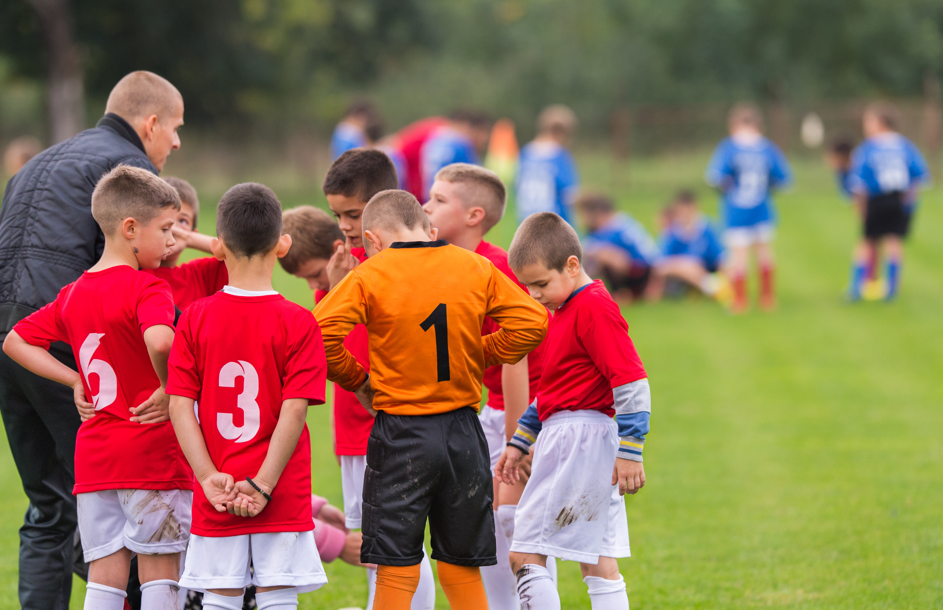 Coach talking with children about soccer game.