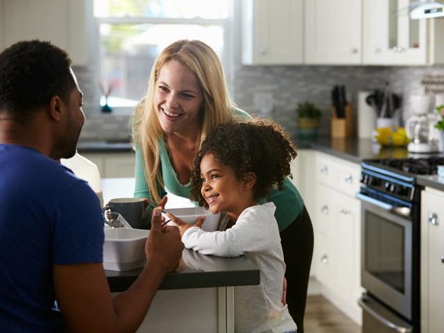 A family smiling in a kitchen