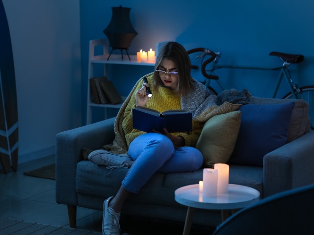 woman sitting in dark with candles during power outage