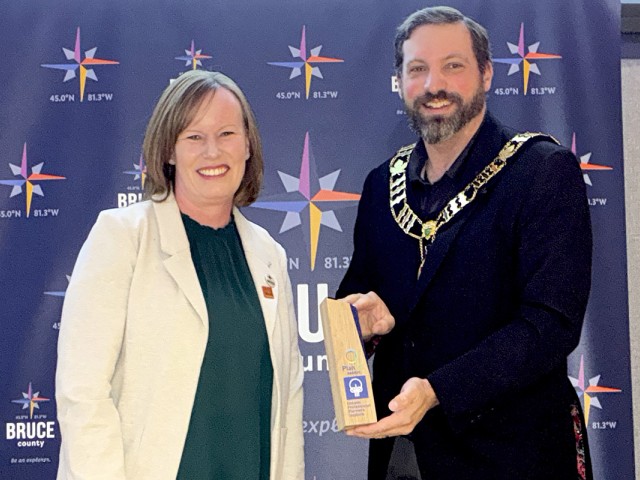 From left: Claire Dodds receives recognition from Bruce County Warden Luke Charbonneau for being awarded the 2025 Registered Professional Planner Leadership Award.