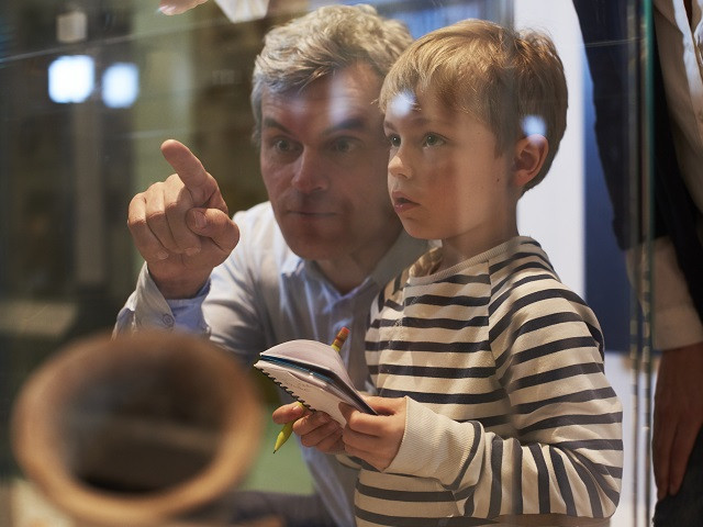 a man pointing out something behind glass to a child