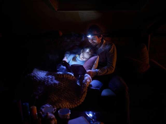 Man and child reading in dark with headlamps
