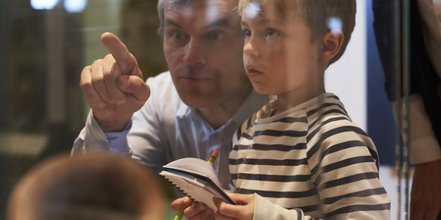 a man pointing out something behind glass to a child