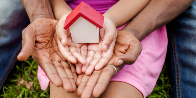 a child holding a tiny birdhouse while an adult holds around the child's hands