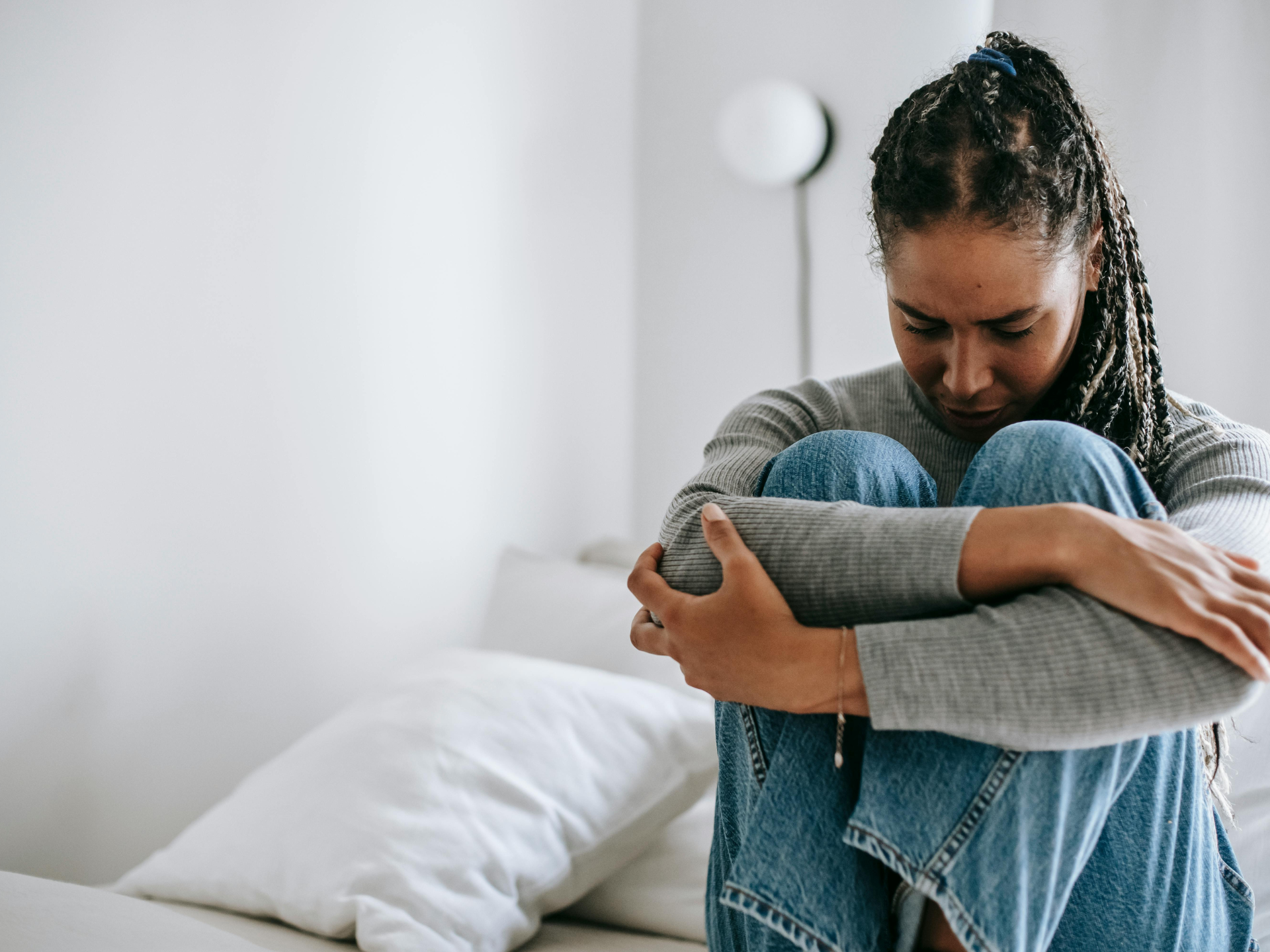 woman sitting on bed with legs tucked up